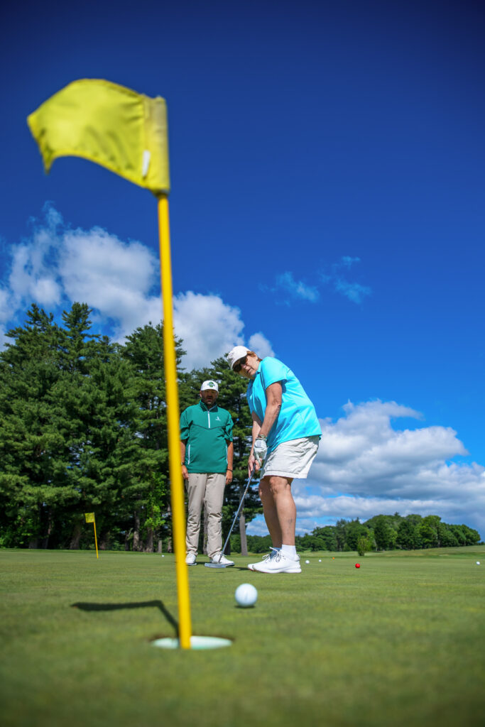 Golfers putting on the green at Candia Woods Golf Links